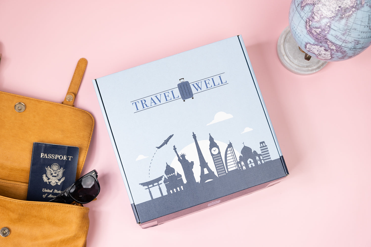 travel well subscription box travel essentials on a table with globe and passport in a bag